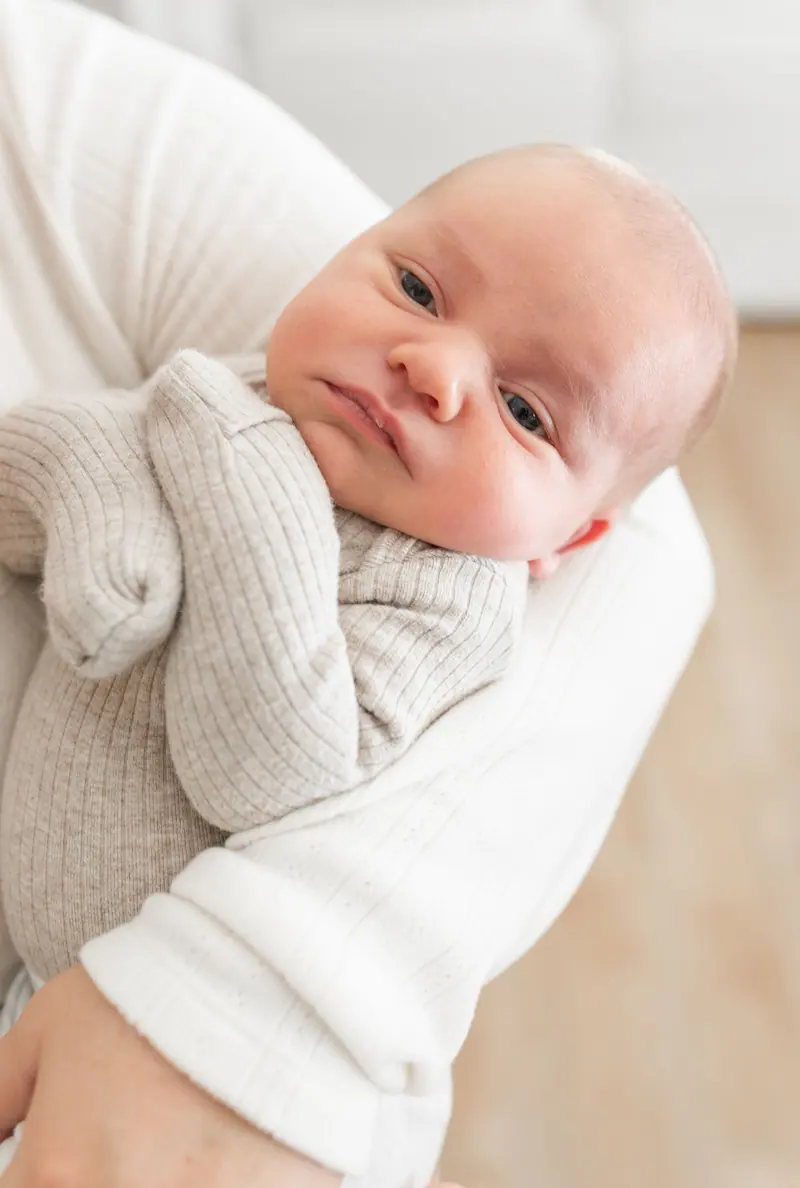 A wide-awake newborn looking out over a parent's shoulder