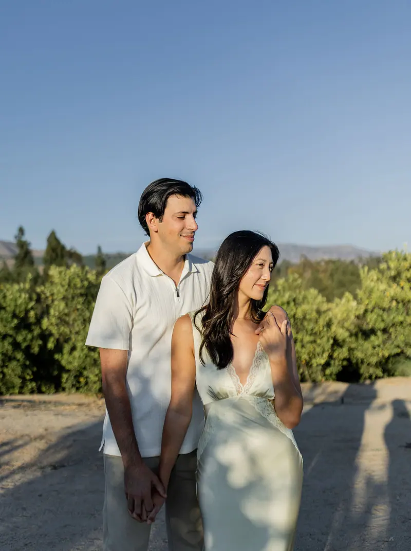Engaged couple on a hillside under open sky