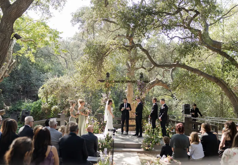 Guests seated for the ceremony beneath the trees