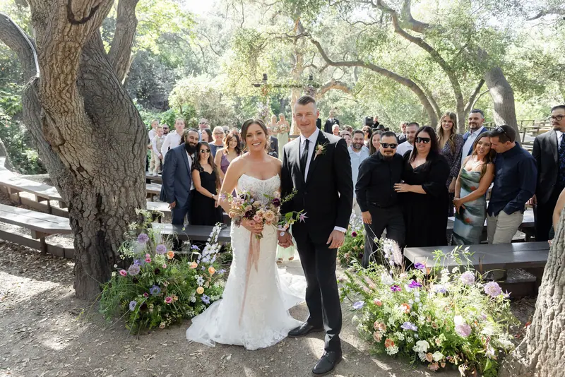 Newlyweds walking back down the aisle as guests stand and watch