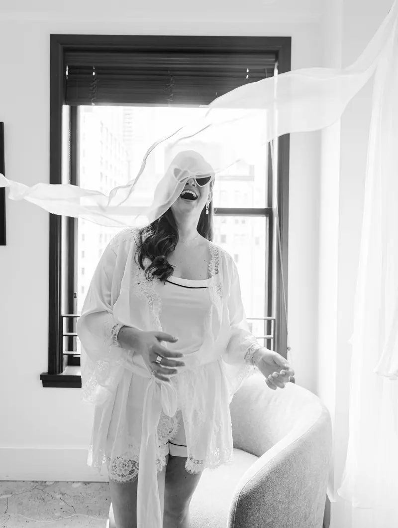 A bride laughing as her veil blows across her face